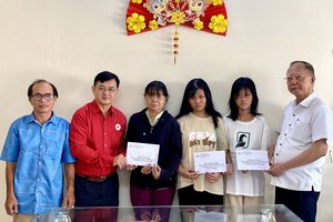 第五郡红十字会主席黎勳丰（左二）；该会副主席兼穗城会馆理事长卢耀南（右一）向已故黎氏红雪家属转交款项。