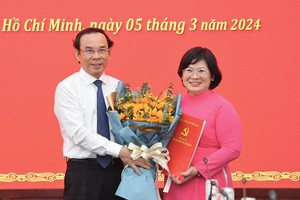 文氏白雪（右）同志从市委书记阮文年手中接过人事委任《决定》和祝贺鲜花。（图：武松）