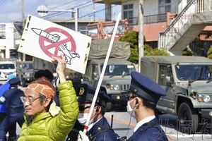 抗议人群对着开往自卫队胜连分屯地的车队举起标语牌。3月10日上午摄于冲绳县宇流麻市。（图：共同社） 