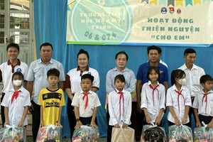 文献大学外语系副主任赖开荣与书法俱乐部成员向贫困生派发礼物。