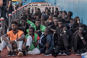 图为 2023年10月12日移民在西班牙下船后坐在地上。（图：AFP）