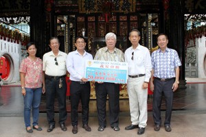 本市潮州义安会馆理事会代表把赠款交给本报领导。