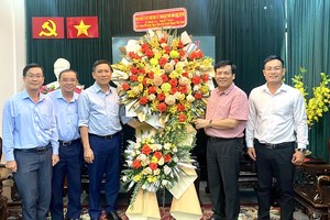 市委民运处副主任陈春田（左三）向本报主编阮玉英（右二）赠送鲜花祝贺。