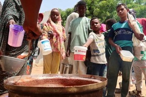 苏丹民众排队等候分发食物和用水。（图：THE GUARDIAN）