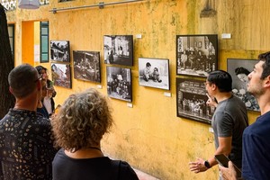 外国游客在河内古街参观图片展。