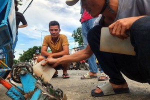 志愿组的陈文原（右）采用自造的磁铁盒在１号国道上吸到的一大堆菱形钉子。（图：孟灵）