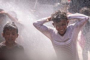 在也门伊卜的流离失所者营地里，一个水泵经修复后喷出水花，孩子们在水中玩耍。（图：联合国）