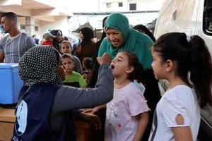 一位祖母带着两个孙女到加沙的一处健康中心接种脊髓灰质炎疫苗。（图：联合国）