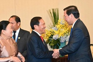 市人委会主席潘文迈（右）与老挝建国阵线中央委员会副主席康莱‧西巴育亲切握手互相致意。（图：越勇）