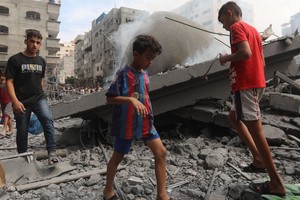 在加沙的难民营，孩子们走在被空袭摧毁的房屋的废墟中。（图：联合国）