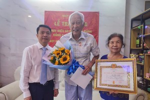 陆进义党员（中）荣获60年党龄纪念章。