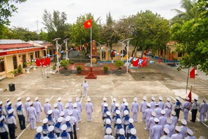 在迎风飘扬的祖国神圣黄星红旗下，在主权碑前，干部、战士和群众列队进行升旗仪式。（图：辉凤）