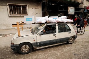 巴勒斯坦民众在加沙城驾车运送援助物资。（图：路透社）