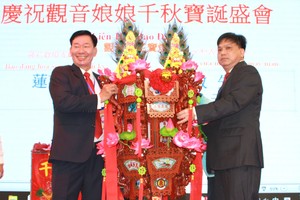 该庙副理事长叶其达（左）向邓奕敏先生移交“莲花宝灯”。