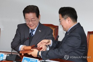 4月9日，在首尔汝矣岛国会，李在明（左）将槌棒交给党鞭朴赞大。（图：韩联社）