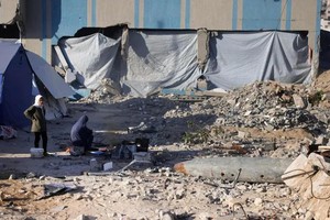 4月19日，加沙地带加沙城一个由警察局改建的避难所附近，一名流离失所的巴勒斯坦妇女和另一名妇女在未爆炸弹药附近的帐篷前。（图：AFP）