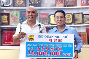 二府会馆理事赖学良（左）把3000万元赠报经费交给本报编委文忠孝。