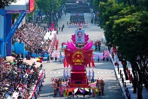 越南社会主义共和国国徽模型车引领阅兵游行方队。紧随其后的是载着胡志明主席肖像的车辆在本市中心行驶，两侧是数千人民挥手欢迎。
