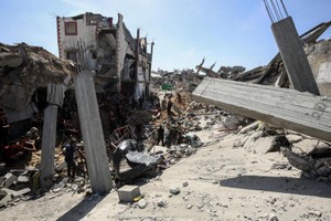 5月16日，在加沙地带北部杰巴利耶难民营，人们查看以军袭击后的建筑废墟。（图：新华社）