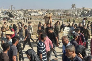 5月27日，在加沙地带南部城市拉法，民众从“加沙人道主义基金会”运营的一个物资分发中心领取救援物资。（图：新华社）