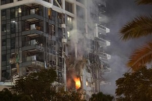 6月13日，特拉维夫市中心一栋建筑据称遭到伊朗导弹袭击，建筑物冒出火光和浓烟。 （图：法新社）