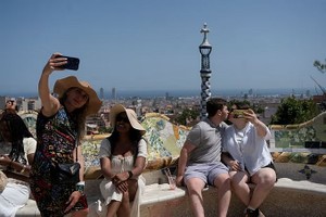 游客们在巴塞罗那自拍，活动人士在此召开了一场关于过度旅游的会议。（图：路透社）