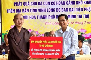 释慧功和尚向永隆省新乂乡人委会副主席文功智移交救济品。