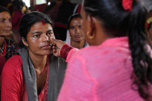 一名女性社区卫生志愿者通过检查尼泊尔农村一名妇女的下眼睑是否颜色苍白来筛查其是否患有贫血。（图：联合国）