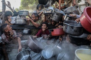 7月14日，人们在加沙城的一处食物分发点领取免费食物。（图：联合国）