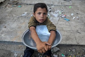 7月14日，一名儿童在加沙城的一处食物分发点等待领取免费食物。（图：新华社)