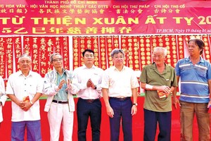 在“慈善挥春”活动上，华文《西贡解放日报》慈善组向清贫华人赠送现金，让大家欢度新春佳节。