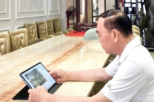 刘根全先生透过平板电脑，静阅华文电子报。