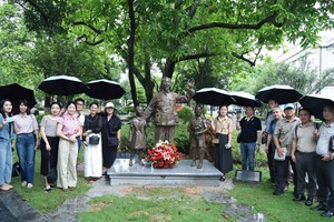  越南主要新闻机关代表团在南宁市育才学校校园内的胡志明主席塑像前合影留念。