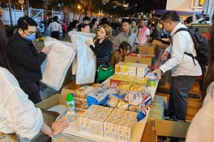 11月26日，受火灾影响的居民在跨部门援助站领取救援物资。