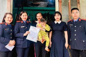 岘港市第十区域人民检察院代表与奠盘坊人委会向幼儿T.N发放出生证。