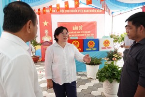  胡志明市市委副书记文氏白雪与安富东坊42号投票区的选举服务工作人员交流。