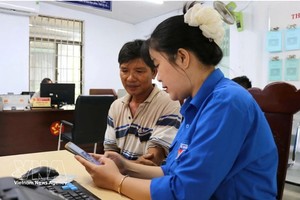 青年向河静省当地居民介绍并指引使用“i-HaTinh”数字公民应用程序的操作流程。