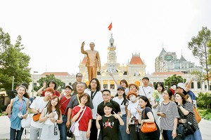 众多游客在胡志明市人委会办事处前的胡志明主席雕像下拍照留念。图：勇芳