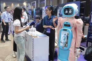 参观者在Qualcomm展台了解老年人护理机器人模型。图自越通社