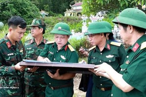 顺化市军事指挥部副政委何文爱大校（左三）在地图上确定烈士安葬位置。图自越通社
