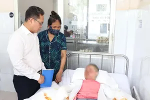 胡志明市越南祖国阵线委员会副主席范明俊慰问、鼓励小U。图:MH
