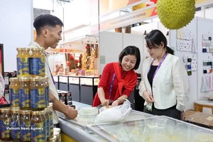 附图：在2025年第22届中国—东盟博览会上，越南企业代表向中国客商推介榴莲饼产品。投资越通社