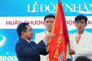 胡志明市人委会主席阮文得将一等劳动勋章佩挂在市口腔颌面医院传统旗帜上。（图:黄雄）