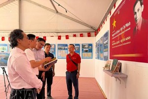 《人民报》代表向越南驻法国大使Kalamoungkhoune Souphanouvong（中）介绍有关胡志明主席和越南争取民族独立历程的展览内容。图自越通社