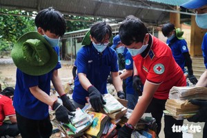 共青团胡志明市市委团员、青年处理被水浸坏的书籍。图：陈怀