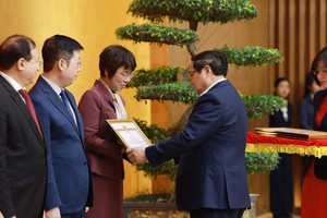 政府党委书记、政府总理范明政向《越通社》社长武越庄颁发政府党委的奖状。图：越通社