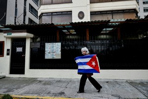 2026年3月4日，厄瓜多驻古巴原大使卡列在厄瓜多首都基多的古巴大使馆外，手持古巴国旗。图：路透社