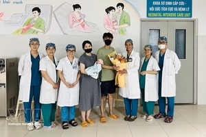 岘港妇产儿科医院医护人员向即将出院的一家三口赠送鲜花表示祝贺。图：越通社