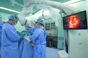 胡志明市医药大学医院神经外科主任张青情博士、医生使用显微镜进行脑部手术。 