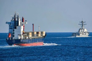 美国军舰护送一艘货船通过霍尔木兹海峡。图源：NAVY